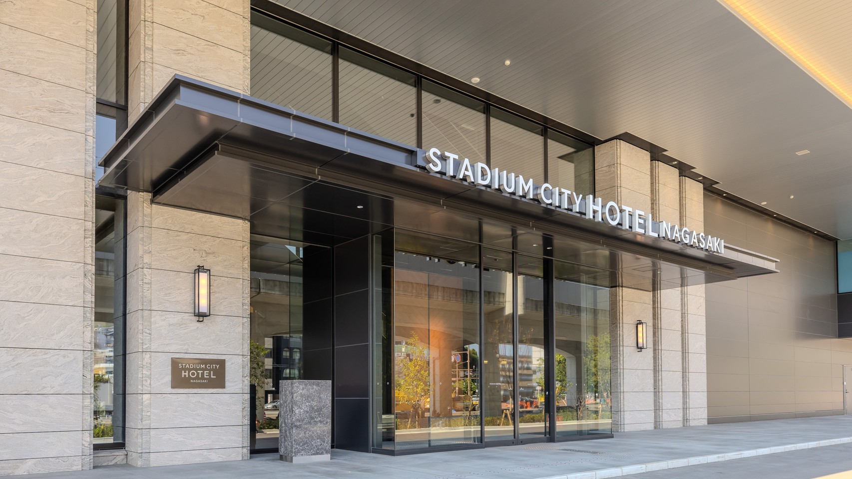 スタジアムシティホテル長崎の入口。ガラス張りの玄関の上に、宿の名前が白い文字で出ている